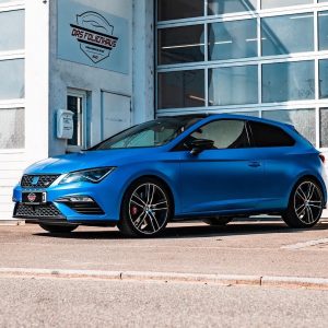 Ein blauer folierter Seat steht vor dem Garagentor von einer Werkstatt von ,,Das Folienhaus"