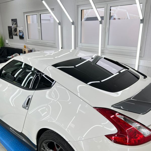 Von oben wurde ein weißer Nissan fotografiert. Er ist foliert, sodass sich dir Lampen extrem gut auf widerspiegeln lassen