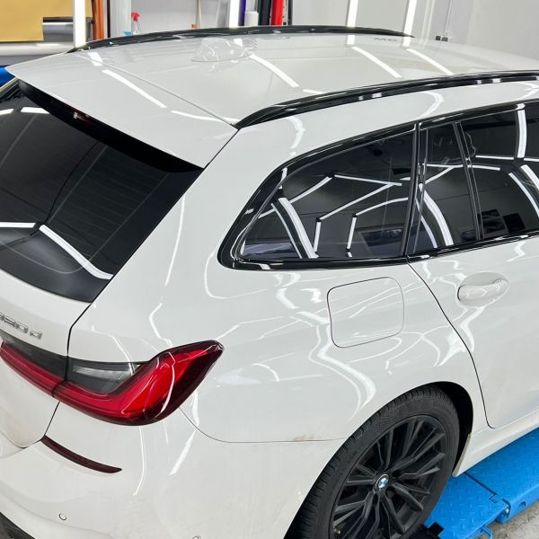 Weißer BMW neu foliert. Die getönten Scheiben und Lackierung spiegeln das Licht..